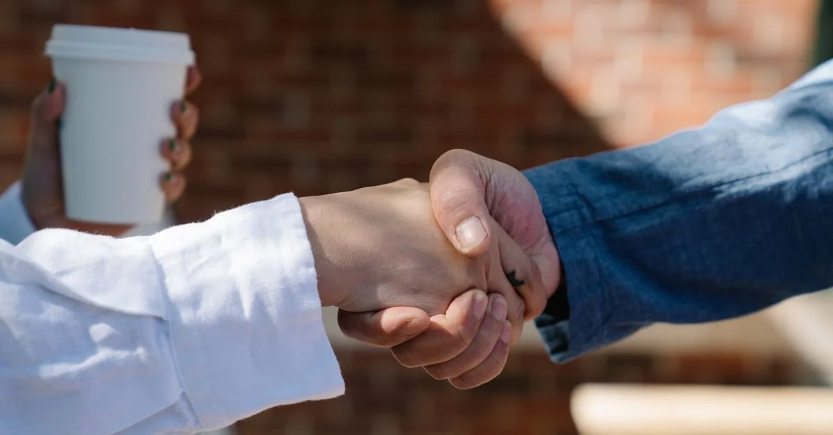 Gros plan d'une poignée de main entre deux adultes, symbolisant un accord ou un partenariat.