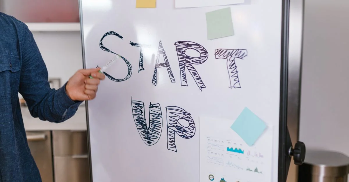 Une personne présente une idée de startup sur un tableau blanc dans un cadre de bureau, mettant l'accent sur l'entrepreneuriat.