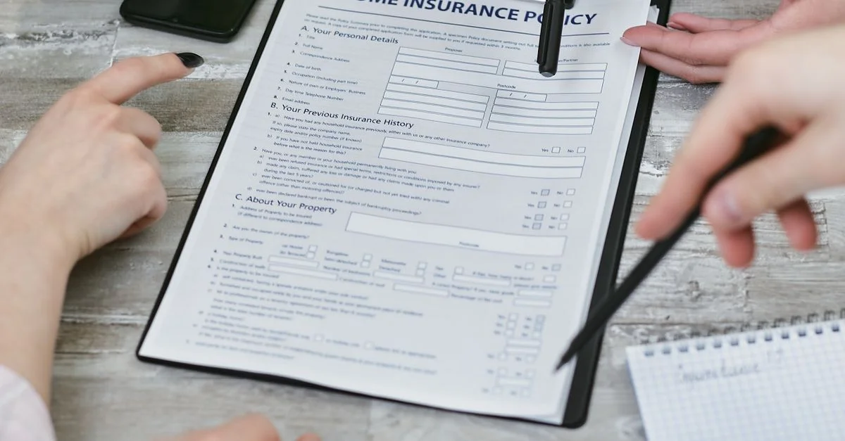 Trois individus collaborant sur un document de police d'assurance habitation. Éléments comprenant un clipboard, des notes et des mains pointant.
